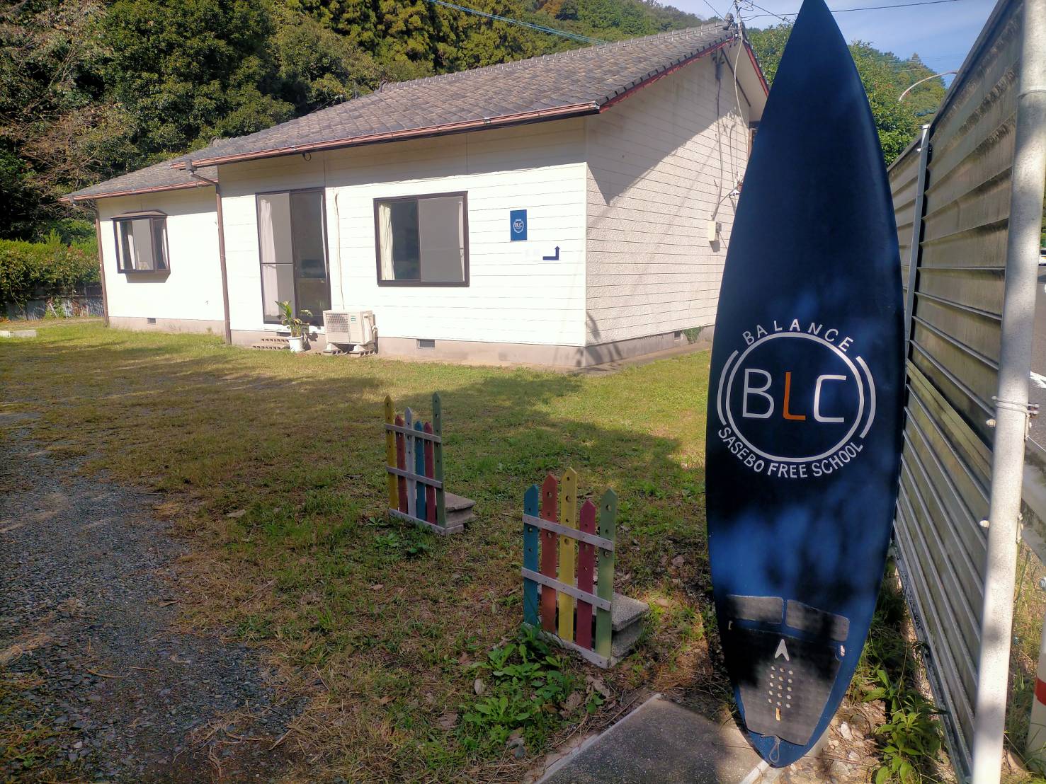 バランスの平屋の建物と、目印の青いBLCサーフボード